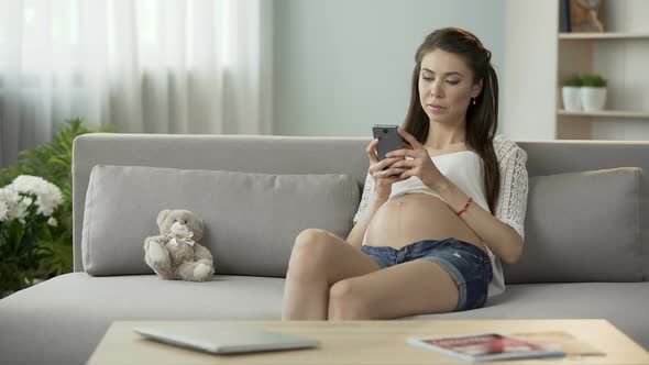 Expecting Woman on Couch Typing Message on Mobile Phone, Social Networking alt