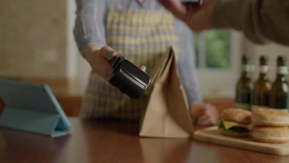 Paying with Contactless Terminal and Mobile Phone for Take Away Food in Cafe alt