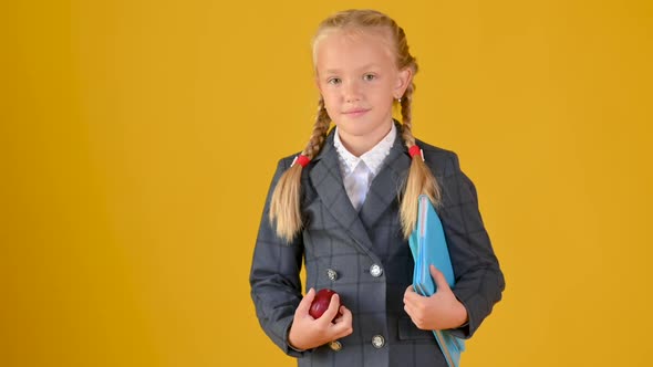 teenage girl schoolgirl in a school uniform with a backpack and books in her hands