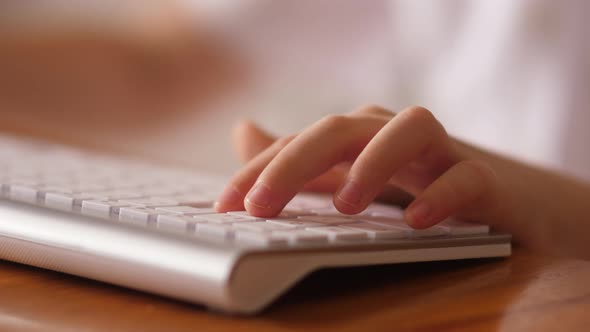 Child fingers typing on the white computer keyboard
