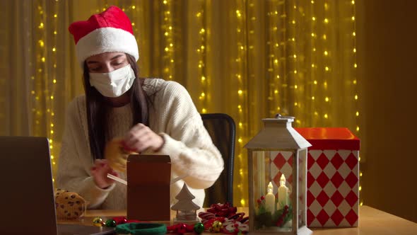 Woman Packing Christmas Present While Having Video Chat During Pandemic