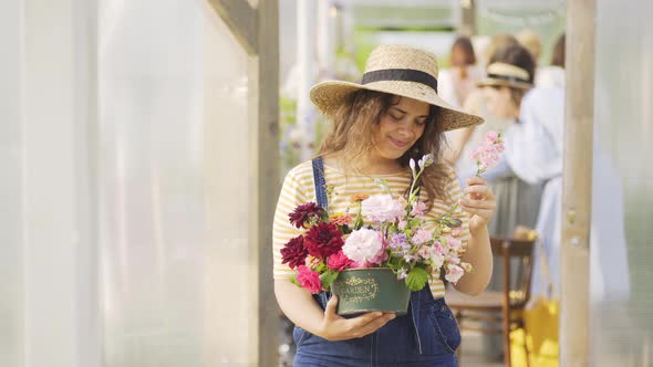 Pretty Woman in Straw Hat Arranges Bouquet in Cardboard Box