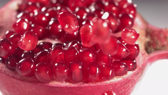 Pomegranate Grains Rolls Down on Surface of Broken Pomegranate in Slow Motion alt