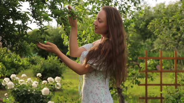 Woman Touching Tree Branches in Garden