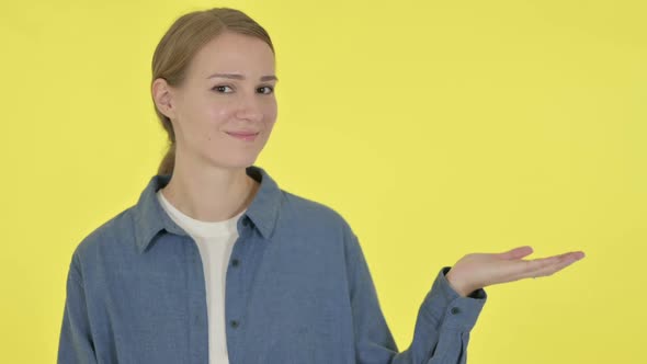 Young Woman Holding Product in Hand on Yellow Background alt