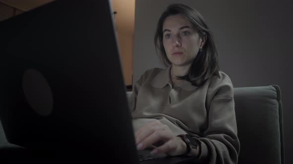 Woman using laptop at night in living room