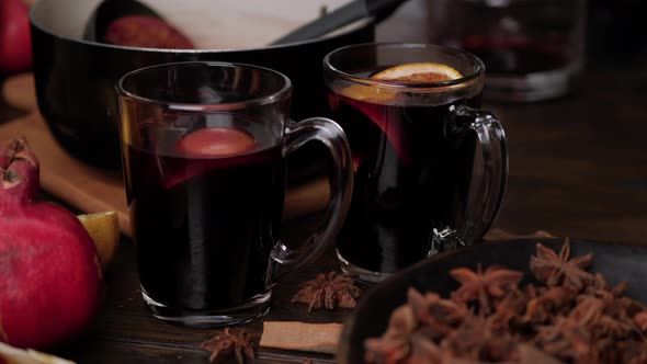 Female Hands Put Slices of Oranges and Anise Stars in Clear Glass Mugs with Mulled Wine. Close Up