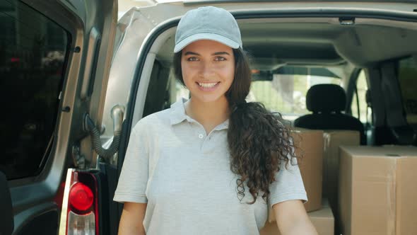 Slow Motion Portrait of Young Woman Courier Standing Near Van Full of Parcels alt