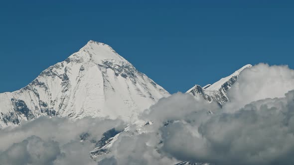 Timelapse Clouds Swirl Over a Mountain Valley a Snowy Peak in the Distance alt