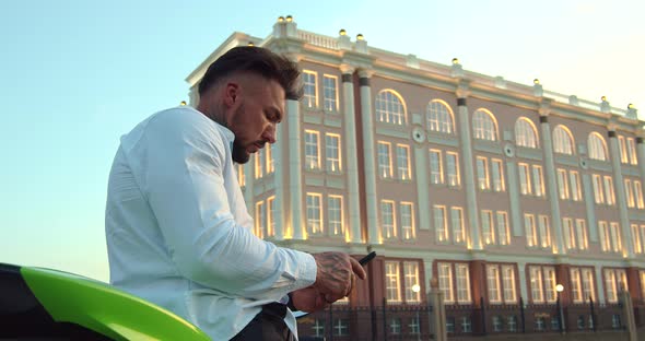 Man Sitting on Motorcycle and Using Smartphone in City