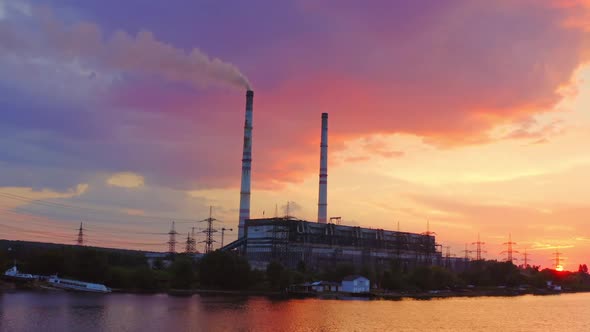 Industrial area at sunset. Factory near the river on the beautiful pink sky. alt