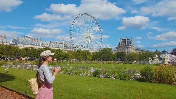 Young tourist taking photo in a park in Paris alt