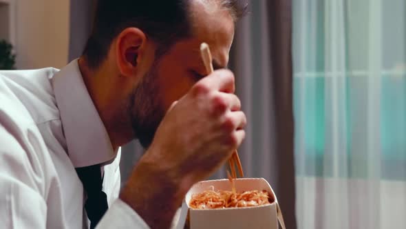 Close Up of Businessman with Tie Eating Noodles From a Box alt