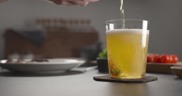 Pour Apple Cider in a Tumbler Glass on Concrete Countertop with Window on Background