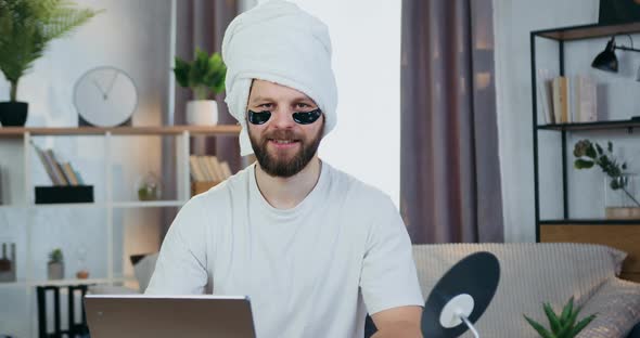 Bearder Looking Into Camera with Collagen Refreshing Eye-Patches and Towel Around His head alt