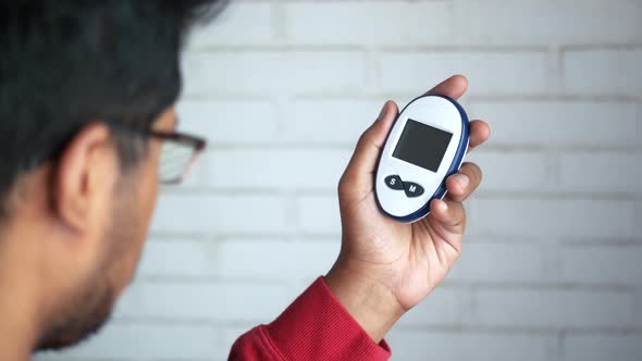 Young Man's Hand Holding Glucose Meter alt
