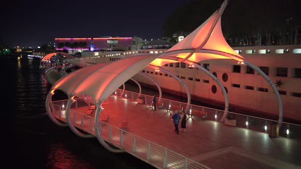 Couple walking on the Tampa Riverwalk at night alt