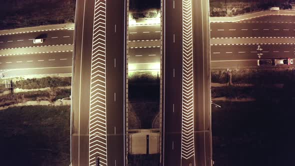 Top aerial shot of night traffic on a highway showing cars and lanes of light with bridges