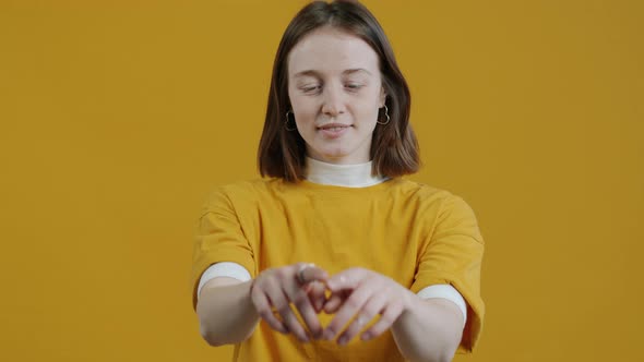 Slow Motion Portrait of Loving Young Woman Drawing Heart Shape in Air and Smiling alt