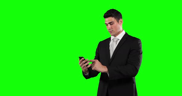a Caucasian man in suit using a phone in a green background