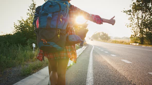 Couple of Travellers Hitchhiking on Empty Road at Sunset alt