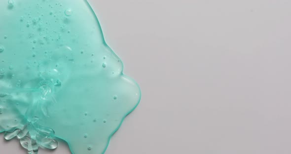 Blue cream liquid gel serum flowing down on silver texture
