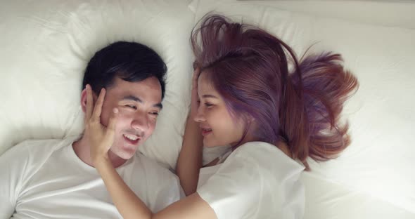 Happy Asian husband and pregnant wife spend time together in the bedroom in the morning.