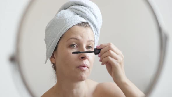 Woman applying mascara on eyelashes 4K 2160p 30fps UltraHD footage - Female in front of make-up mirr