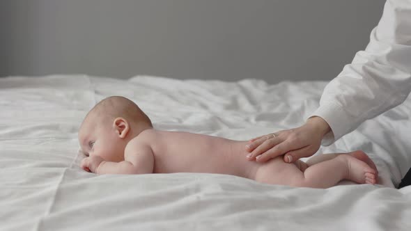 Caring Mother Massaging Her Naked Newborn Boy alt
