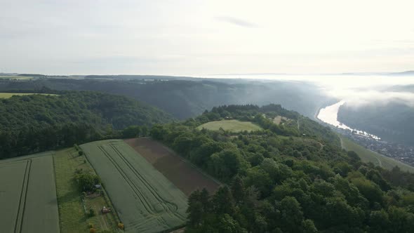 The picturesque river valleys of the Moselle wine region on a sunny and foggy morning. Panning aeria alt