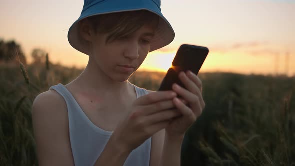 Funny Boy Uses the Phone in the Golden Wheat Field at Sunset