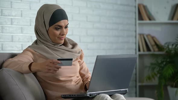 Modern Arab Housewife Typing Card Number on Laptop, Banking Online, Purchase alt