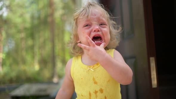 Close Up Portrait of Little Funny Cute Blonde Girl Child Toddler in Yellow Dirty Bodysuit Crying