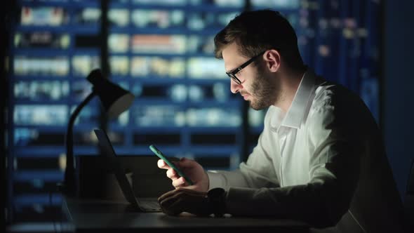 Office Building with Businessman Using Mobile Phone and Standing By the Office Window alt