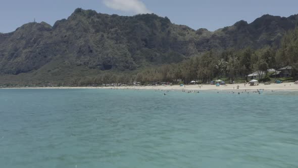 CINEMATIC DRONE FLIES LOW OVER HAWAIIAN OCEAN NEAR BEACH
