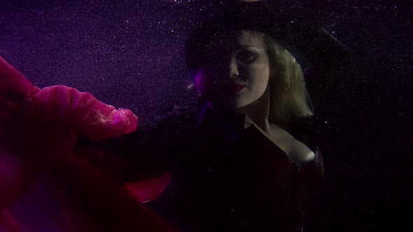 Mysterious Woman with Hat Is Floating in Dark Deepness of Sea or Ocean alt