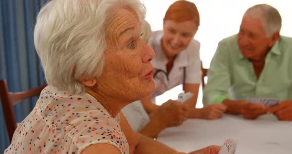 Senior woman talking to senior man while sitting at dinning table alt
