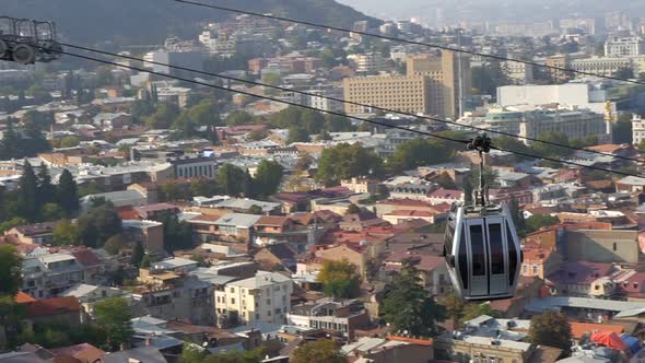 Cableway Car Hanging Above the Tbilisi City in Georgia with the View of Old Buildings on Background alt