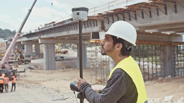 Construction engineer working with GPS equipment on a large highway construction site alt