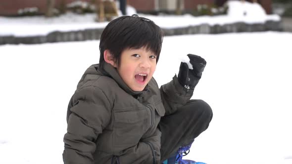 Cute Asian child playing on snow in the park alt