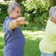 Video of relaxed biracial senior couple practicing yoga in garden