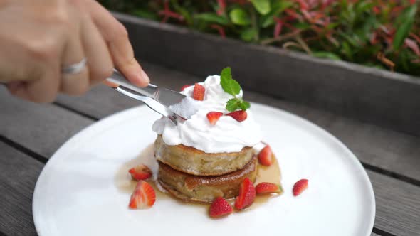 Close Up of Two Gluten Free Pancakes with Plant Based Whipped Cream Being Cut with Cutlery alt