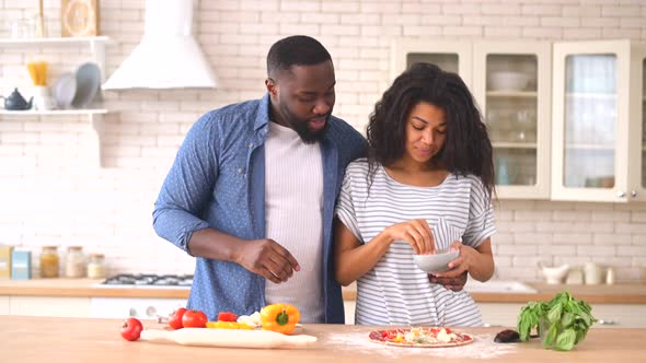 Happy Multiracial Couple Preparing Pizza Together at Home alt