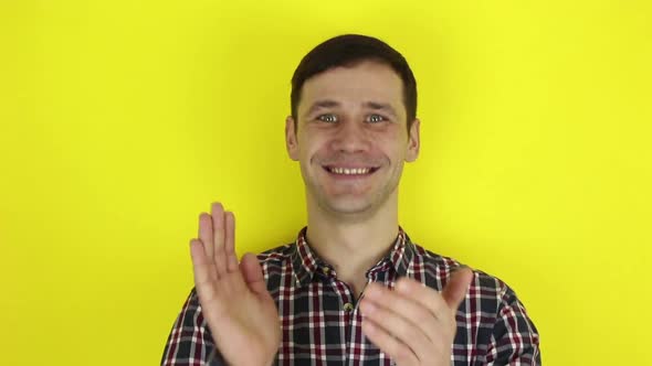 A Funny Handsome Guy Actively Expresses His Enthusiasm and Claps His Hands. Portrait on a Yellow