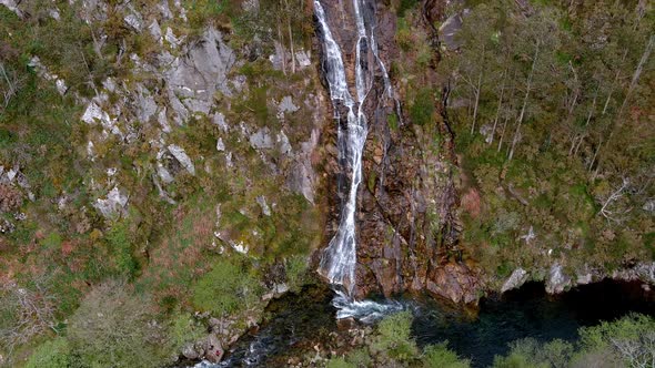 Aerial backward moving shot over waterfall of the Sor River at the viewpoint of Aguas Caídas, Manón, alt
