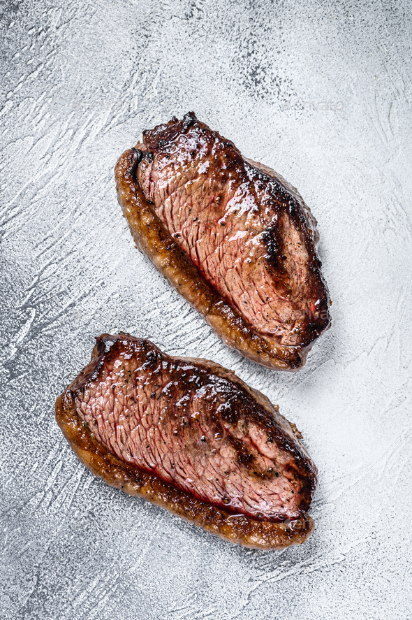 Grilled top sirloin cap or picanha steak. White background. Top view