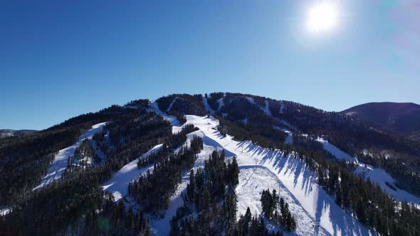 Drone shot over looking a ski mountain with the sun in frame alt