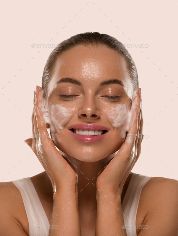 Woman face mask wash soap close up clean skin. Color background yellow