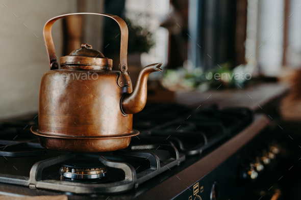 Bronze kettle in modern kitchen. Old vintage teapot on gas stove. Preparing  tea Stock Photo by StudioVK