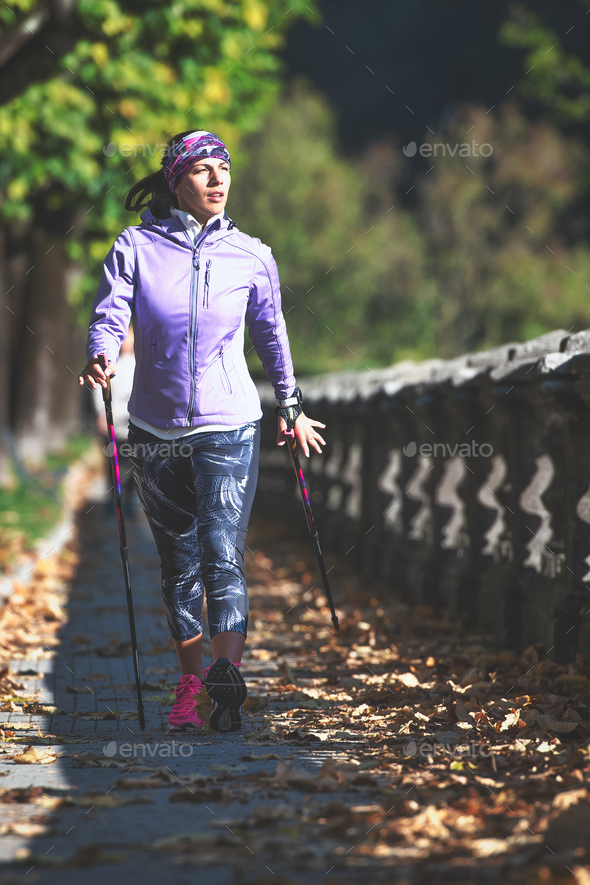 Nordic walking on sidewalk. A young woman practices - Stock Photo - Images